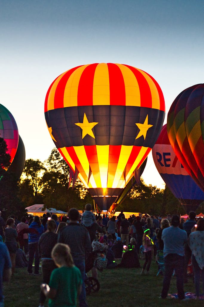 Colorful hot air balloons light up the evening sky at a lively festival.